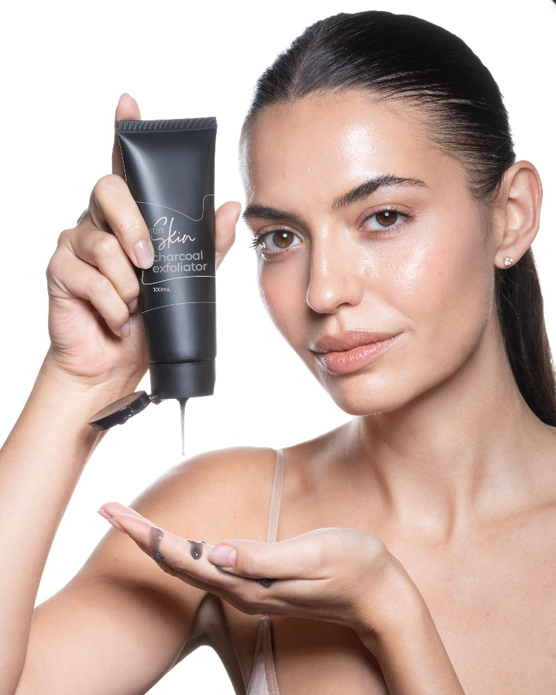 Woman holding a black skincare product with visible charcoal on her palm against a white background